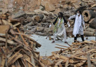 A woman pulls away her crying relative as she reacts to the burning funeral pyre of their family member who died of COVID-19, at an open crematorium set up at a granite quarry on the outskirts of Bengaluru, India, Wednesday, May 5, 2021. (AP Photo/Aijaz Rahi)