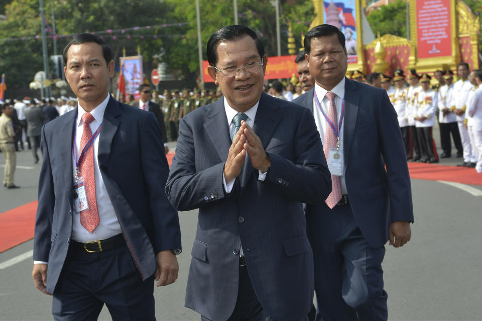 Cambodian Prime Minister Hun Sen, center, greets his government officers during the country's 66th Independence Day from France, at the Independence Monument in Phnom Penh, Cambodia, Saturday, Nov. 9, 2019. The leader of the banned Cambodia National Rescue Party, Sam Rainsy was boarding a fly in Paris for his attempt to return home to challenge his country's longtime autocratic leader as the security inside the country was on high alert and beefed up. (AP Photo/Vithy Soth)