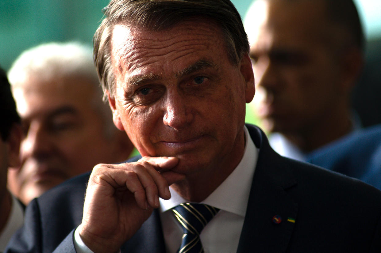 President Jair Bolsonaro, hand to his chin, looks pensive. 