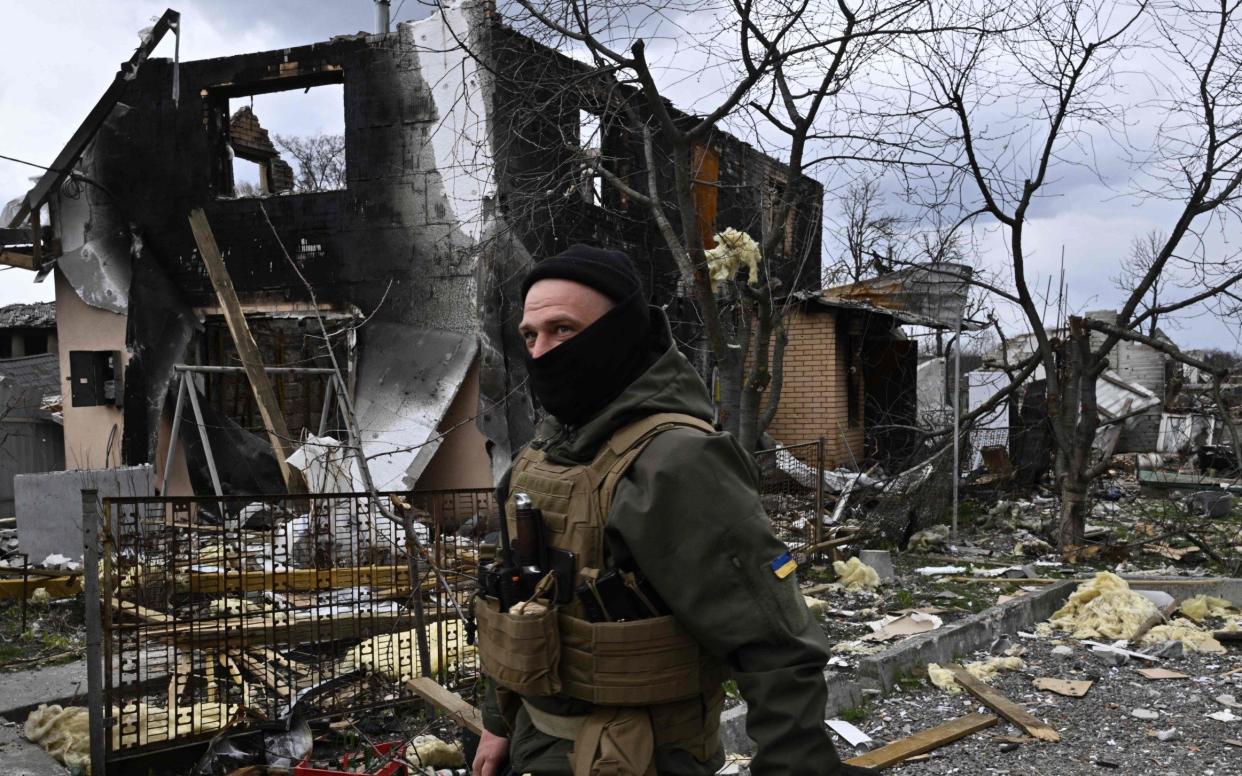 A member of Ukraine's territorial defence force outside a bombed-out house north east of Kyiv - GETTY IMAGES