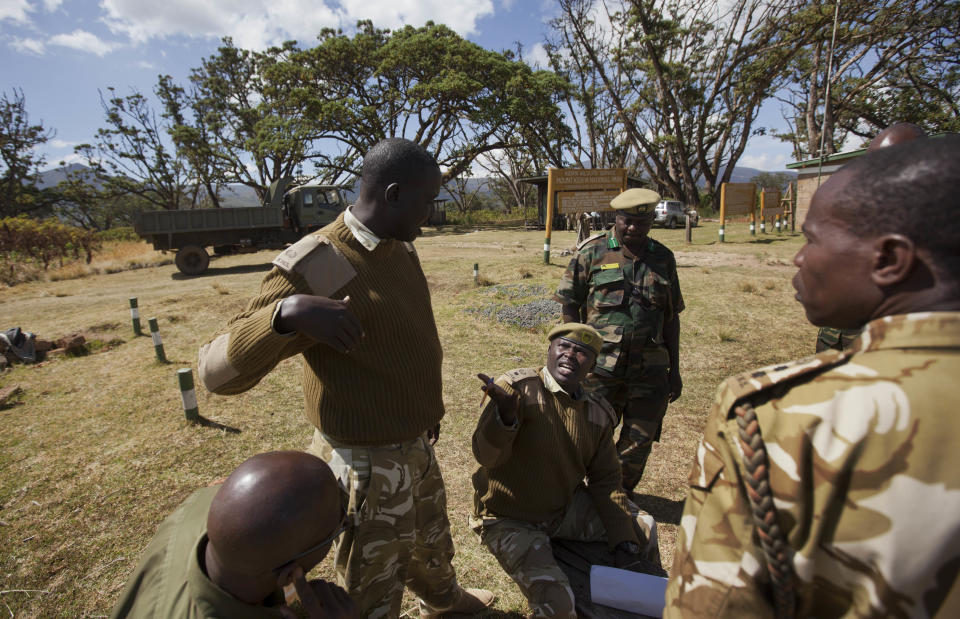 Simon Gitau, deputy warden of Mt. Kenya National Park, seated center, discusses strategy with other members of the Kenyan Wildlife Service as they attempt to put out forest fires on the slopes of Mount Kenya, the second-highest peak in Africa at 5,199 meters (17,057 feet), in Kenya Tuesday, March 20, 2012. Fires that have been raging across Mount Kenya may have been set by poachers trying to create a diversion from their illegal attacks on animals, a wildlife official said Tuesday. (AP Photo/Ben Curtis)