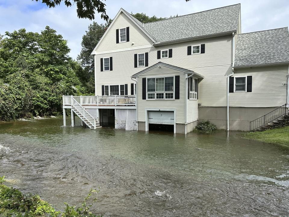 A brook in Leominster, Mass. overflows into the garage of a home following heavy rains overnight, Tuesday, Sept. 12, 2023. (AP Photo/Michael Casey)