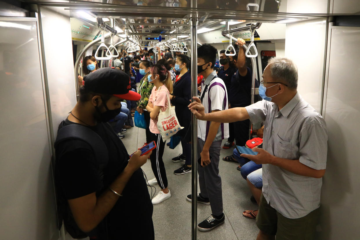 SINGAPORE - JUNE 08:  Commuters wearing protective masks are seen onboard a packed train on June 8, 2020 in Singapore. The authority decided to remove all safe distancing stickers and markers from trains and buses as they deemed it is too challenging for commuters to keep their social distance. From June 2, Singapore embarked on phase one of a three phase approach against the coronavirus (COVID-19) pandemic as it began to ease the partial lockdown measures by allowing the safe re-opening of economic activities which do not pose high risk of transmission. This include the resumption of selected health services, re-opening of schools with school children attending schools on rotational basis, manufacturing and production facilities, construction sites that adhere to safety measures, finance and information services that do not require interactions and places of worship, amongst others. Retail outlets, social and entertainment activities will remain closed and dining in at food and beverage outlets will still be disallowed. The government will further ease restriction by the middle of June if the infection rate within the community remains low over the next two weeks.  (Photo by Suhaimi Abdullah/Getty Images)