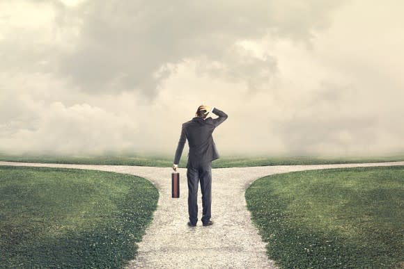 Man with briefcase facing a fork in the road.