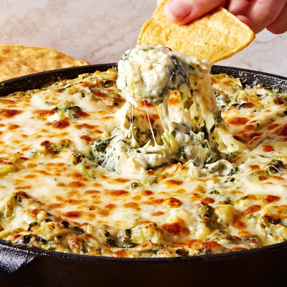 spinach artichoke dip in a cast iron skillet served with tortilla chips