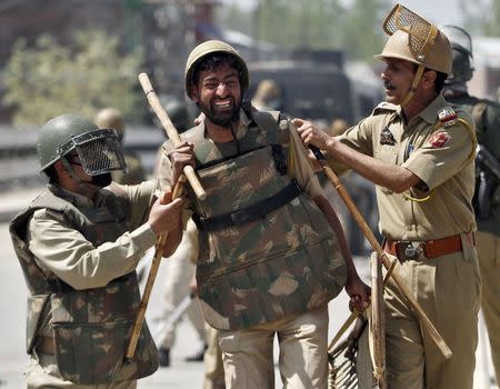 A policeman (C) is being helped by colleagues after he was injured in a clash with Kashmiri protesters during a daylong protest strike in Narbal, north of Srinagar April 18, 2015. REUTERS/Danish Ismail