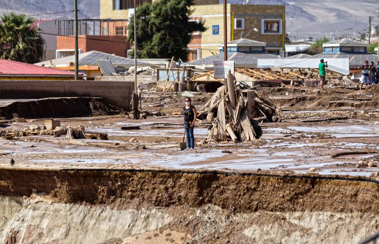 A woman stands in a street that was flooded in Chanaral, after heavy rainfall caused the Copiapo river to overflow, and flooding in parts of the city in nothern Chile, April 1, 2015