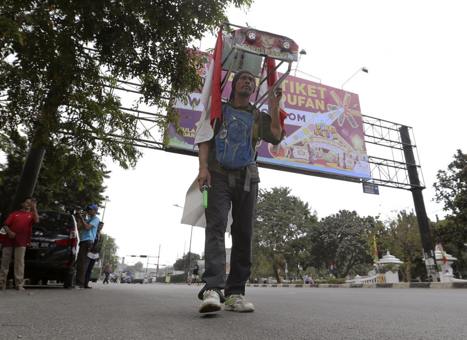 Medi Bastoni, 43, walks backwards in Bekasi, outskirt of Jakarta, Indonesia, Thursday, Aug, 22, 2019. The Indonesian man is walking over 700-kilometer (430-mile) backward from his home in eastern Java to the country's capital to draw awareness of deforestation.(AP Photo/Achmad Ibrahim)