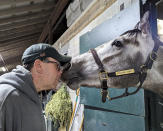 In this photo provided by Josef Lejzerowicz, trainer Joe Lejzerowicz rubs noses with colt Freezing Point, aka “Snowball,” at their barn at Keeneland in Lexington, Ky., March 19, 2023. Freezing Point was euthanized after sustaining a leg injury during a race on the undercard of the Kentucky Derby, May 6, 2023. He was one of two horses to die from injury that day and among 12 over the past month at the home of the Derby. (Laura Lejzerowicz via AP)