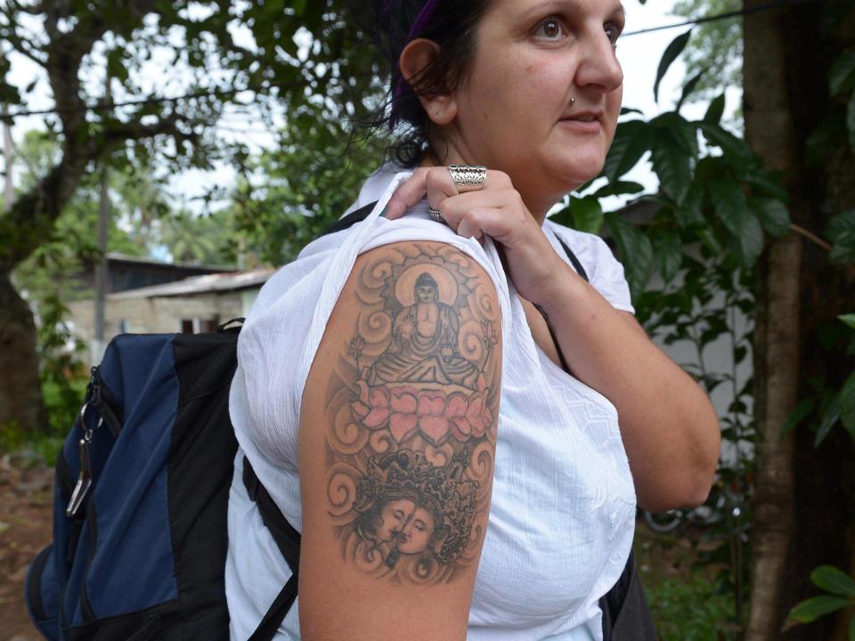 British tourist Naomi Coleman poses for a photograph to display a tattoo of the Buddha on her upper arm, after she was arrested at Sri Lanka's main international airport in 2014: AFP/Getty Images