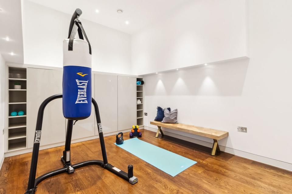 a gym with exercise equipment with wooden floor and built in shelves in the denbigh close notting hill home