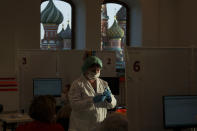 FILE - A medical worker prepares a shot of Russia's Sputnik Lite coronavirus vaccine at a vaccination center in the GUM, State Department store, in Red Square with the St. Basil Cathedral in the background, in Moscow, Russia, Oct. 26, 2021. The developer of Russia's Sputnik V vaccine said Monday Nov. 29, 2021, that it will immediately start working on adapting that COVID-19 vaccine to counter the omicron variant. (AP Photo/Pavel Golovkin, File)