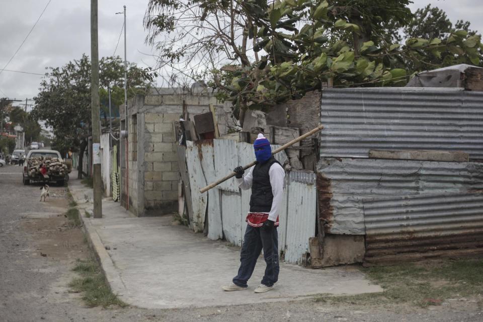 A masked man stands guard at a neighborhood in Veracruz, Mexico, Saturday, Jan. 7, 2017. As looting as largely subsided in Mexico, following a 20 percent hike in gasoline prices, neighborhoods in affected áreas have taken to guarding themselves from potential looters. (AP Photo/Felix Marquez)