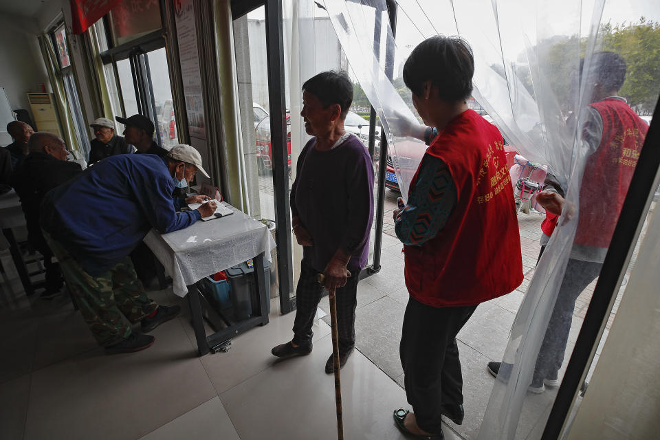 An elderly woman is welcomed by red vest volunteers as she arrives to Kang's canteen, the Harmonious and Happy Home for a free vegetarian lunch in Dingxing, southwest of Beijing Thursday, May 13, 2021. China's leaders are easing limits on how many children each couple can have, hoping to counter the rapid aging of Chinese society. (AP Photo/Andy Wong)