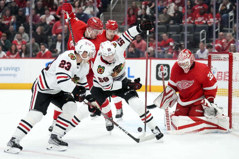 Chicago Blackhawks right wing MacKenzie Entwistle (58) passes the puck between his legs as Detroit Red Wings goaltender Ville Husso (35) defends in the first period of an NHL hockey game Wednesday, March 8, 2023, in Detroit. (AP Photo/Paul Sancya)