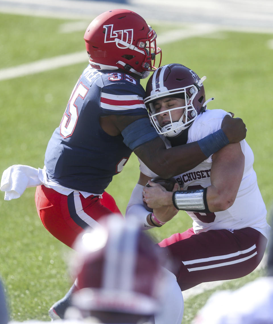 Massachusetts quarterback Garrett Dzuro (9) carries the ball as he is stopped by Liberty linebacker Tyren Dupree (35) during the first half of an NCAA college football game on Friday, Nov. 27, 2020, at Williams Stadium in Lynchburg, Va. (AP Photo/Shaban Athuman)