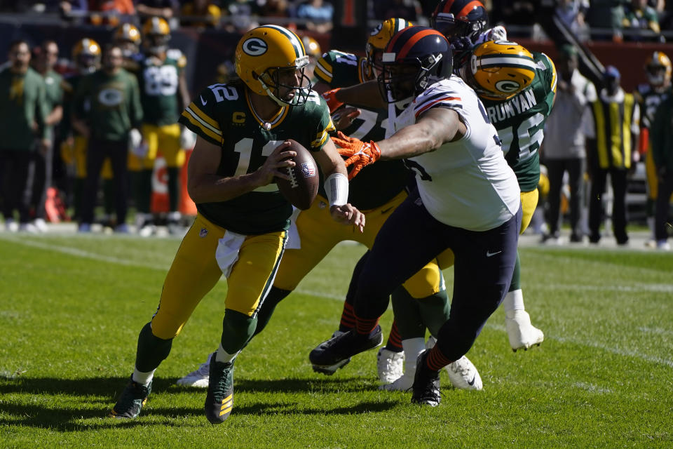 Green Bay Packers quarterback Aaron Rodgers (12) scrambles under pressure from Chicago Bears' Akiem Hicks during the first half of an NFL football game Sunday, Oct. 17, 2021, in Chicago. (AP Photo/Charles Rex Arbogast)