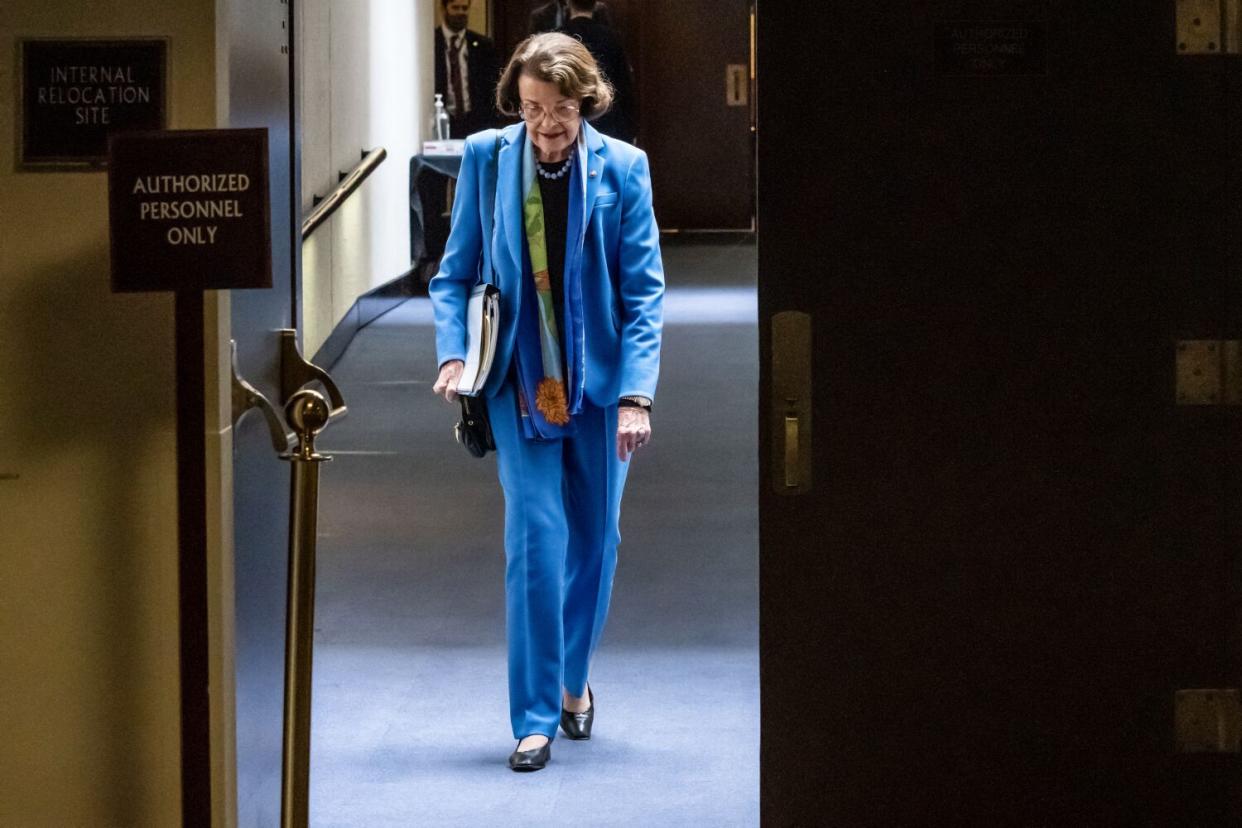 Wearing a blue suit Sen. Dianne Feinstein walks through a corridor on Capitol Hill.