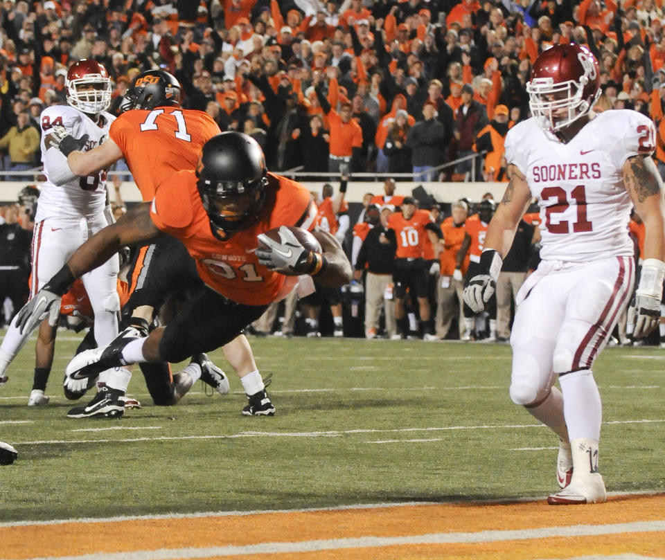 FILE - Oklahoma State's Parker Graham (71) blocks as Oklahoma's Dejuan Miller (24) and Tom Wort (21) watch Oklahoma State's Jeremy Smith (31) score a touchdown during the first quarter of an NCAA college football game in Stillwater, Okla., Dec. 3, 2011. Oklahoma and Oklahoma State will meet on Saturday for the final time before Oklahoma leaves the Big 12 for the Southeastern Conference. (AP Photo/Brody Schmidt, File)