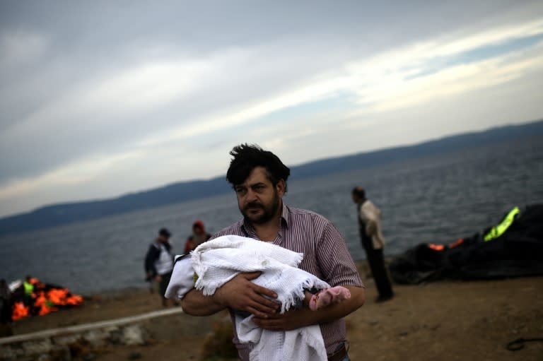 A Syrian man holds his baby early on October 7, 2015 after arriving with other migrants on the Greek island of Lesbos