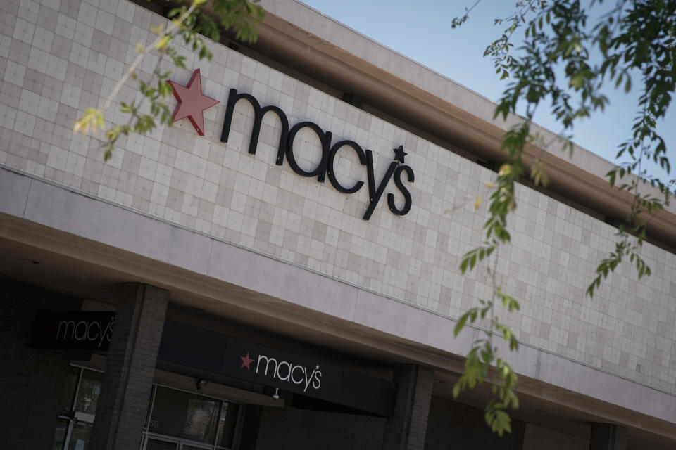 The entrance to a Macy's department store is closed behind barriers and storm shutters remains closed in Santa Ana, Calif., Monday, March 30, 2020. Macy's announced Monday is furloughing most of its 125,000 employees because coronavirus-fueled store closures have caused its sales to all but disappear. (AP Photo/Chris Carlson)