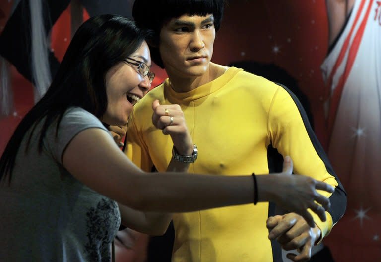 A tourist strikes a pose next to a wax figure of legendary Kung Fu master Bruce Lee, in Hong Kong, on October 25, 2011. Hailed as cinema's first martial arts hero and a cinematic bridge between the cultures of East and West, Lee helped put Hong Kong on the movie world map