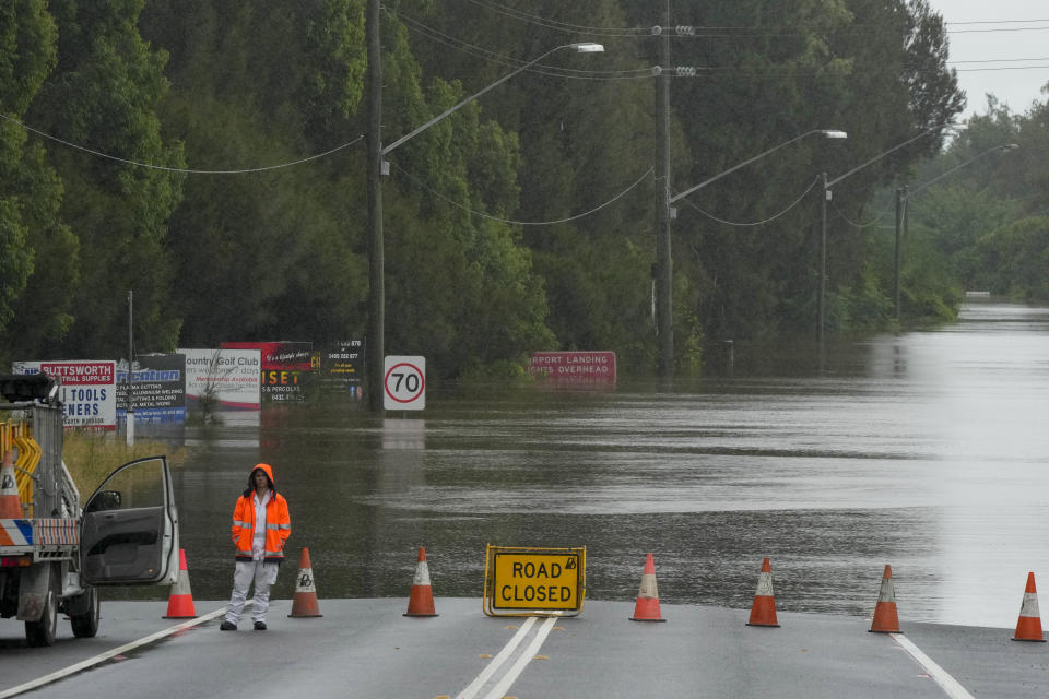 A emergency worker stands by a flooded road at Windsor on the outskirts of Sydney, Australia, Thursday, March 3, 2022.Tens of thousands of people had been ordered to evacuate their homes and many more had been told to prepare to flee as parts of Australia's southeast coast are inundated by the worst flooding in decades. (AP Photo/Rick Rycroft)