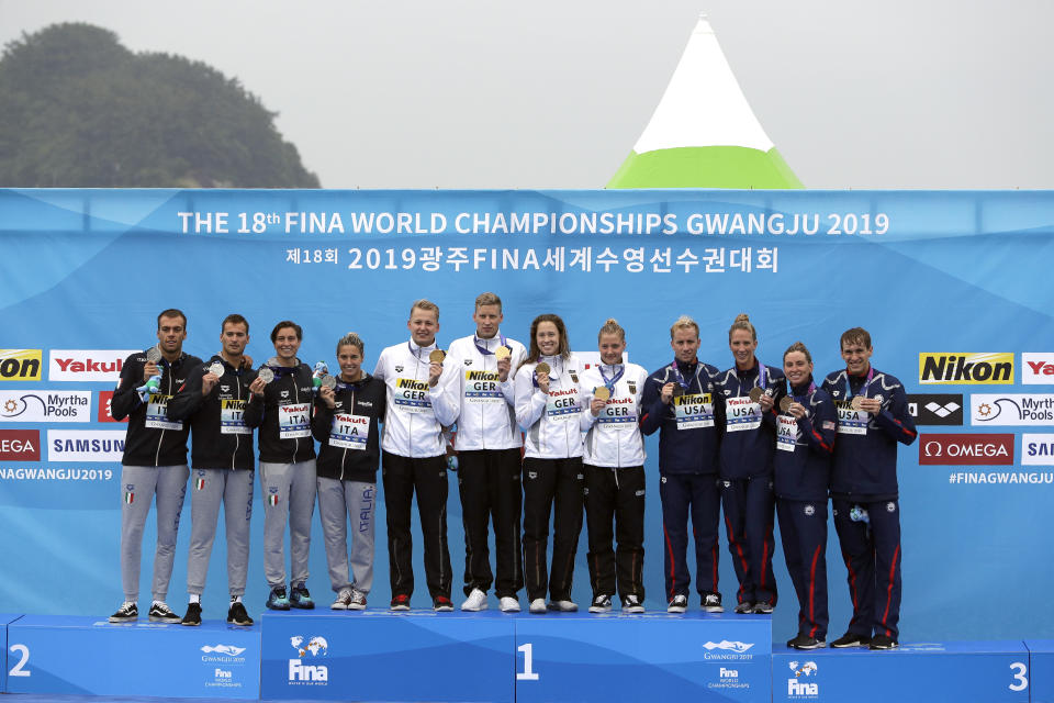 From left, the silver medal team from Italy, the gold medal team from Germany, and the bronze medal team from the United States stand on the podium after the 5km mixed relay open water swim at the World Swimming Championships in Yeosu, South Korea, Thursday, July 18, 2019. (AP Photo/Mark Schiefelbein)