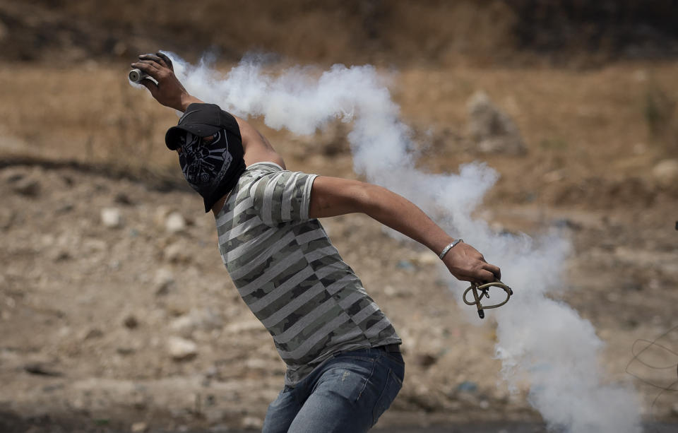 A Palestinian demonstrator throws back a teargas canister during clashes with Israeli forces at the Hawara checkpoint, south of the West Bank city of Nablus Friday, May 21, 2021. (AP Photo/Majdi Mohammed)