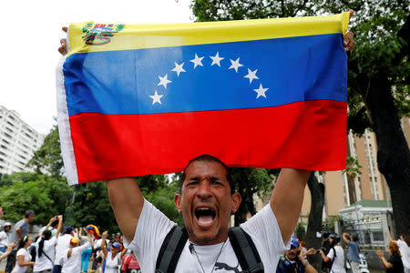 A demonstrator holds a Venezuelan flag as he takes part in a rally to honour victims of violence during a protest against Venezuela's President Nicolas Maduro's government in Caracas, Venezuela, April 22, 2017. REUTERS/Carlos Garcia Rawlins