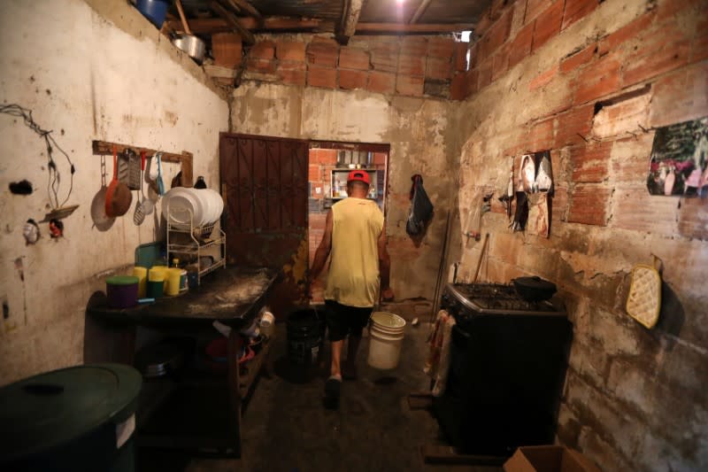 Jose Herrera carries plastic buckets with water into his house in the low-income neighbourhood of Petare amid the coronavirus disease (COVID-19) outbreak in Caracas