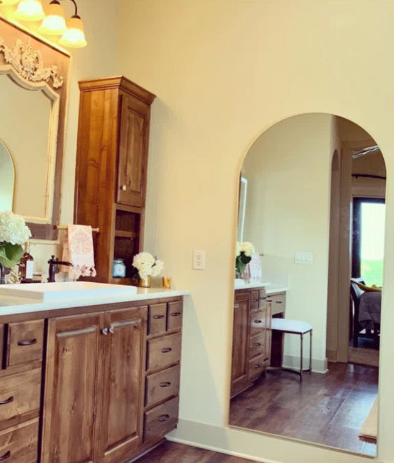 wall mirror with curved top next to bathroom sink