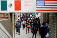 <p>Members of a caravan of migrants from Central America walk towards the United States border and customs facility, where they are expected to apply for asylum, in Tijuana, Mexico April 29, 2018. The sign between the Mexican and the U.S. flag reads: ” We were born in America, we are Americans.” (Photo: Edgard Garrido/Reuters) </p>