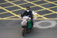 Un hombre que lleva una máscara facial monta una bicicleta llena de alimentos en Wuhan, el epicentro del nuevo brote de coronavirus, en la provincia de Hubei, China