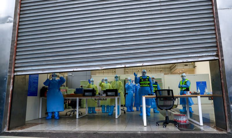 Medical workers and police personnel in protective suits are seen inside a closing makeshift hospital which has been converted from a conference and exhibition center, following the discharge of the last batch of coronavirus patients, in Wuhan