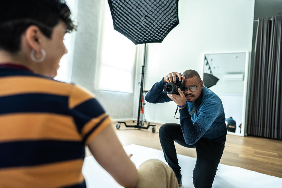 Photographer taking photos of a young model woman at studio