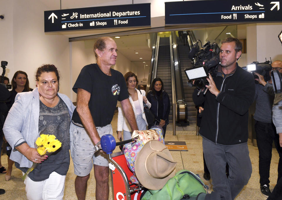 Australian filmmaker James Ricketson, third left, walks with his daughter Roxanne Holmes, second left, after his arrival at Sydney International Airport, Sunday, Sept. 23, 2018. Ricketson arrived two days after his 15-month stint in a Phnom Penh prison ended with clemency granted by Cambodian King Norodom Sihamoni. (Dean Lewins/AAP Image via AP)