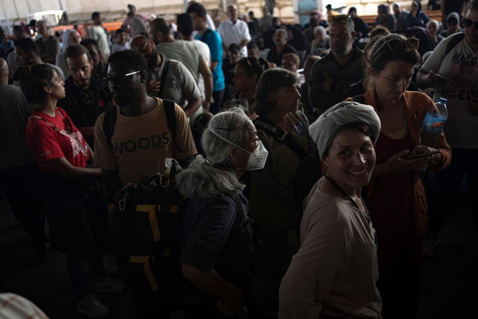 Palestinian people and foreign aid workers wait to cross the border into Egypt.