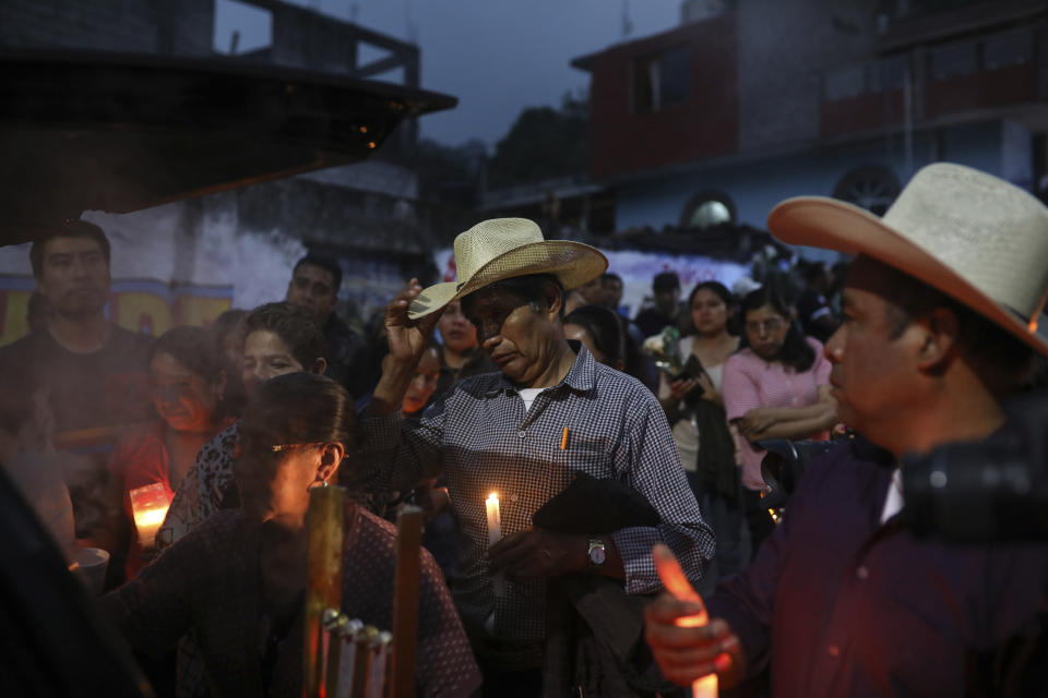 Mourners, some carrying candles, gather around the hearse bringing the body of Maricela Vallejo, the slain 27-year-old mayor of Mixtla de Altamirano, to her aunt's house for her wake, in Zongolica, Veracruz state, Mexico, Thursday, April 25, 2019. Vallejo, her husband, and a driver were assassinated Thursday by multiple gunmen as they drove along a highway. (AP Photo/Felix Marquez)