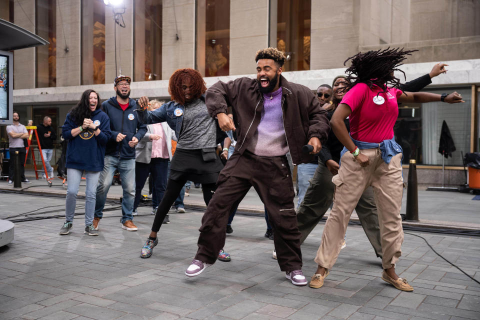 Russell dances in.a brown matching set with people on the plaza outside of Rockefeller Center. (Nathan Congleton / TODAY)