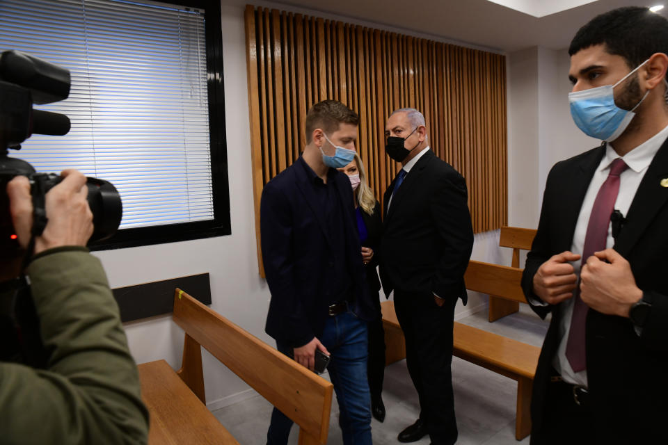 Former Israeli Prime Minister Benjamin Netanyahu, center right, and son Yair, center left, stand in the Tel Aviv Magistrate's Court Monday, Jan. 10, 2022, during a preliminary hearing in a defamation lawsuit. Former Prime Minister Benjamin Netanyahu, his wife and son appeared in the Tel Aviv Magistrate’s court Monday for the opening of their case against Olmert, Netanyahu’s predecessor as Israel’s prime minister. The Netanyahus are suing Olmert for saying they suffered from “mental illness” during an interview last year. (Avshalom Sassoni/Pool Photo via AP)