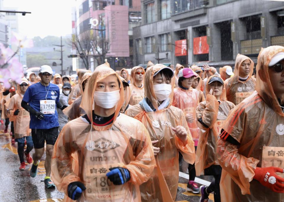 In this Feb. 16, 2020, photo, runners, some wearing masks, compete in a Kumamoto castle marathon in Kumamoto city, western Japan. Organizers of the Tokyo Marathon set for March 1, 2020 are drastically reducing the number of participants out of fear of the spread of the coronavirus from China. The general public is essentially being barred from the race. (Kyodo News via AP)