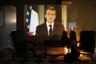 A woman and her daughter watch French President Emmanuel Macron during a televised address to the nation, in Lyon, central France, Monday, Dec. 10, 2018. Facing exceptional protests, French President Emmanuel Macron broke his silence Monday by promising broad tax relief for struggling workers and pensioners, and acknowledging his own responsibility for the nation’s anger. (AP Photo/Laurent Cipriani)