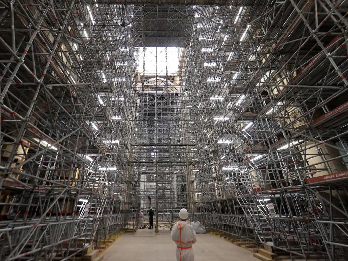 A worker stands under scaffolding at the reconstruction site in the Notre-Dame cathedral in Paris on April 15, 2022.