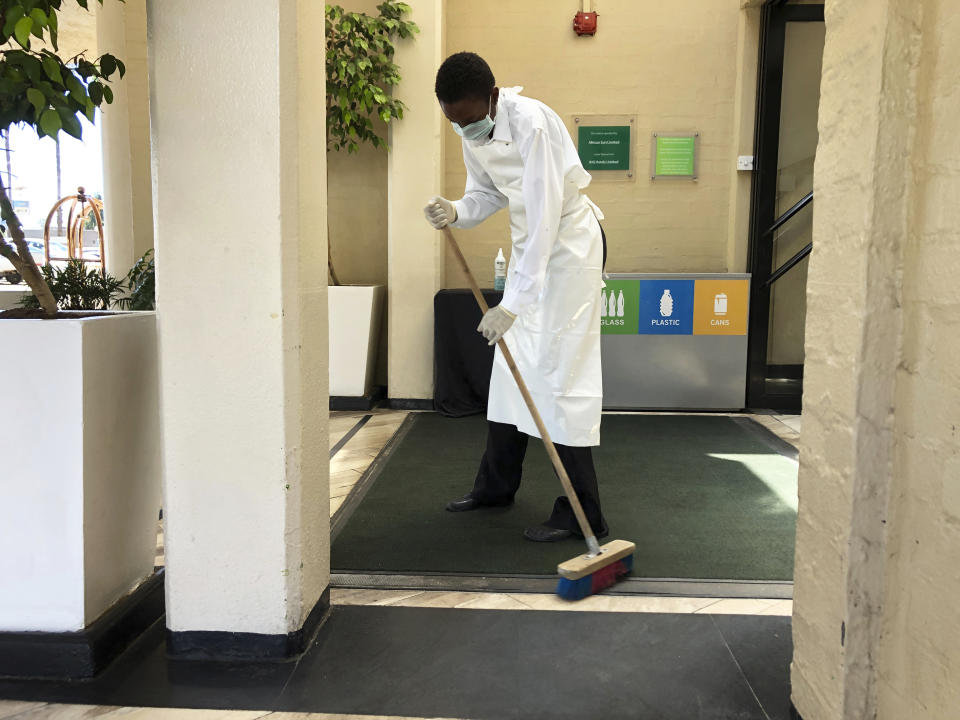 A cleaner wears a mask while sweeping the entrance of a hotel in Harare, Zimbabwe , Wednesday, March, 18, 2020. Zimbabwean President Emmerson Mnangagwa said that the country is cancelling its Independence Day celebrations scheduled for April 18, and declared the outbreak of the coronavirus, a national disaster. For most people the new coronavirus causes only mild or moderate symptons.For some it can cause more severe illness, especially in older adults and pepole with existing health problems.(AP Photo/Tsvangirayi Mukwazhi)