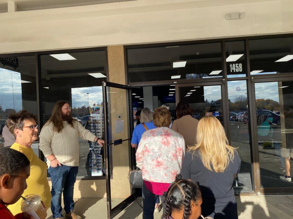 Larry Green, district manager of Discount Fashion Warehouse in the Appleseed Shopping Center, holds the door for the waiting crowd of shoppers after the ribbon cutting for the grand, re-opening of the retail store in Mansfield.