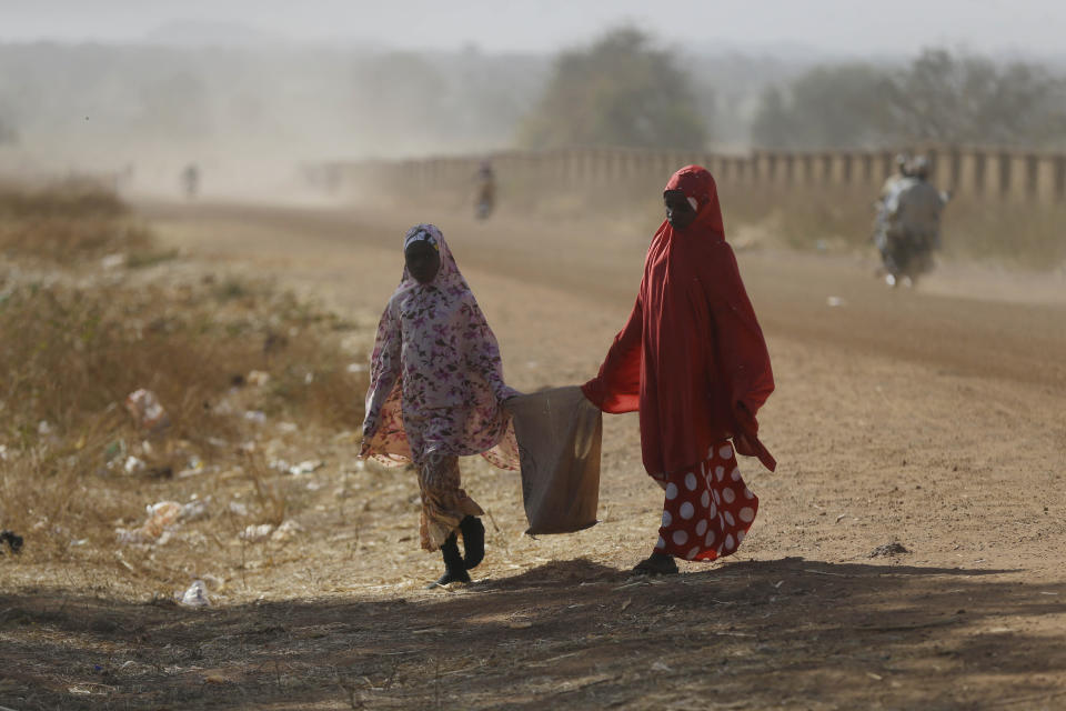 Two women walk past the Government Science Secondary School in Kankara, Nigeria, Tuesday, Dec. 15, 2020. Rebels from the Boko Haram extremist group claimed responsibility Tuesday for abducting hundreds of boys from a school in Nigeria's northern Katsina State last week in one of the largest such attacks in years, raising fears of a growing wave of violence in the region. (AP Photo/Sunday Alamba)