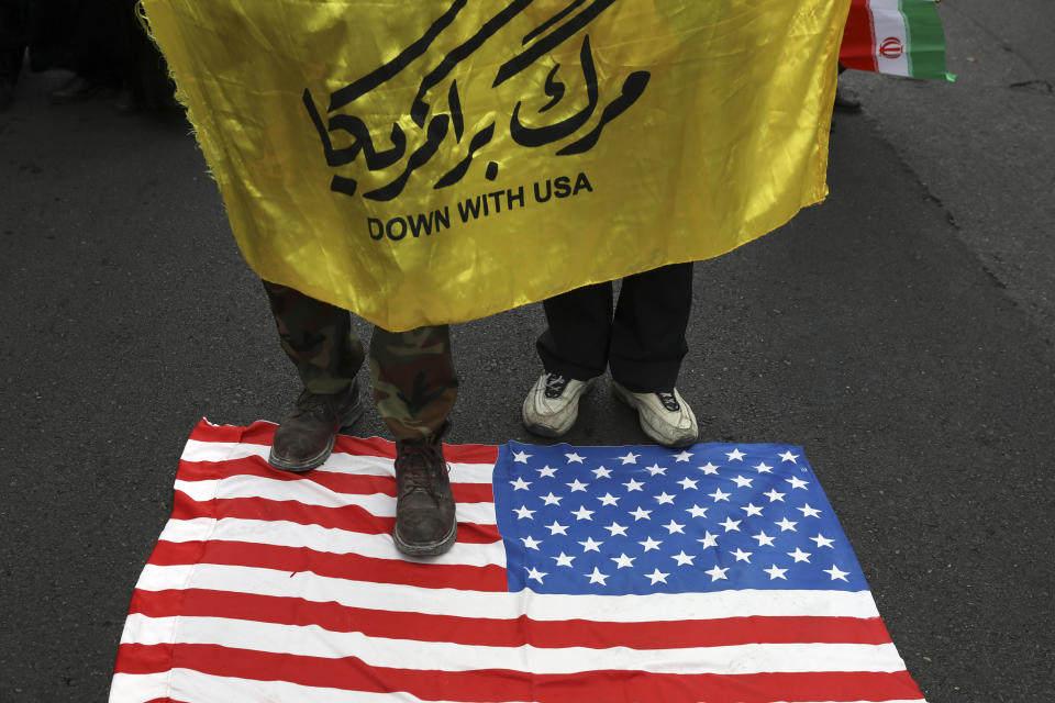 Demonstrators hold an anti-U.S. banner as they stand on a makeshift U.S. flag during an annual rally in front of the former U.S. Embassy in Tehran, Iran, Monday, Nov. 4, 2019. Reviving decades-old cries of "Death to America," Iran on Monday marked the 40th anniversary of the 1979 student takeover of the U.S. Embassy in Tehran and the 444-day hostage crisis that followed as tensions remain high over the country's collapsing nuclear deal with world powers. (AP Photo/Vahid Salemi)