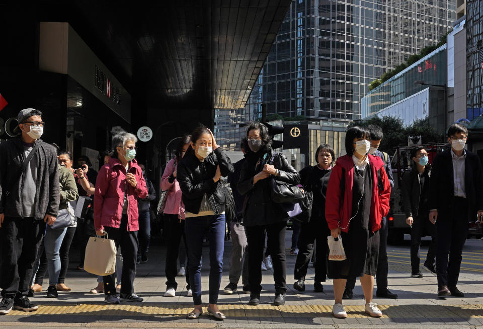 People wearing face mask walk at a downtown street in Hong Kong Friday, Feb. 21, 2020. COVID-19 viral illness has sickened tens of thousands of people in China since December. (AP Photo/Vincent Yu)