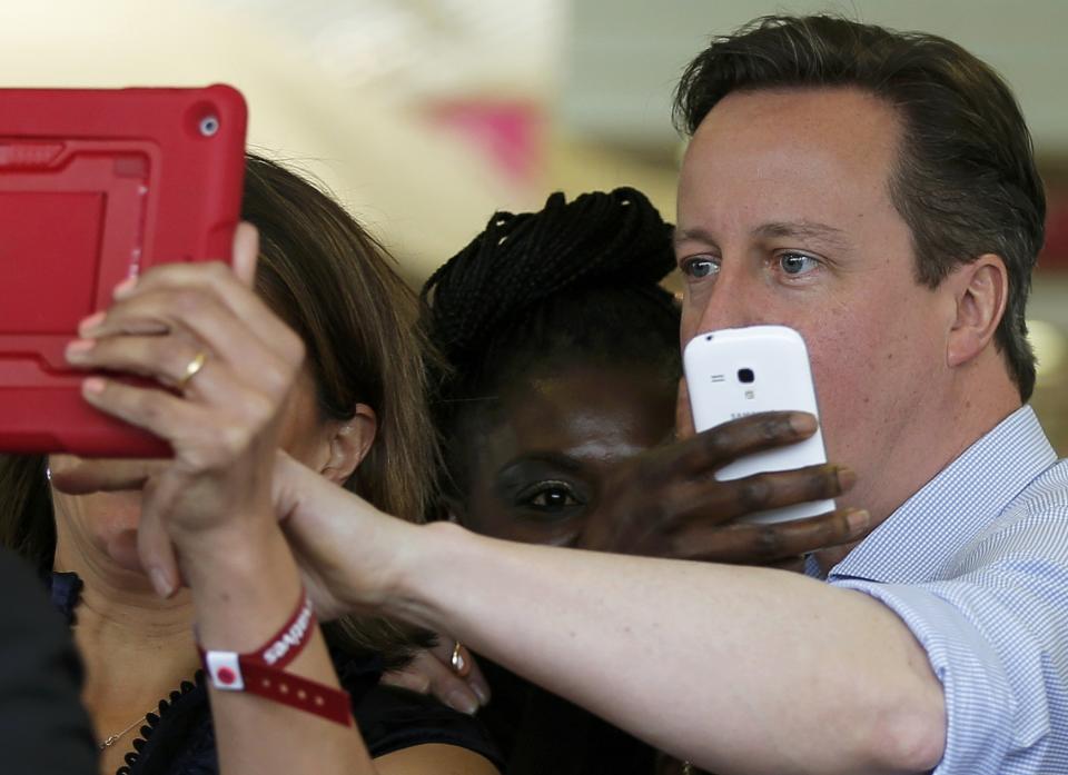 Britain's Prime Minister David Cameron poses for selfie photographs with supporters at a Squires garden centre in Twickenham, London, Britain May 5, 2015. Britain will go to the polls in a national election on May 7. REUTERS/Peter Nicholls